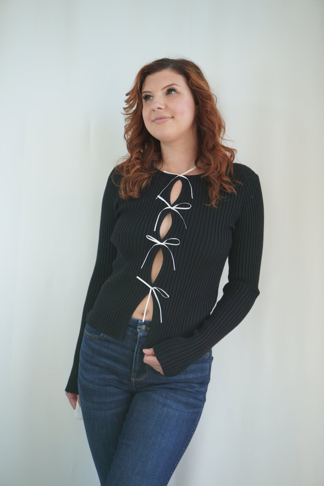Black ribbed sweater with open front tied with multiple bow details