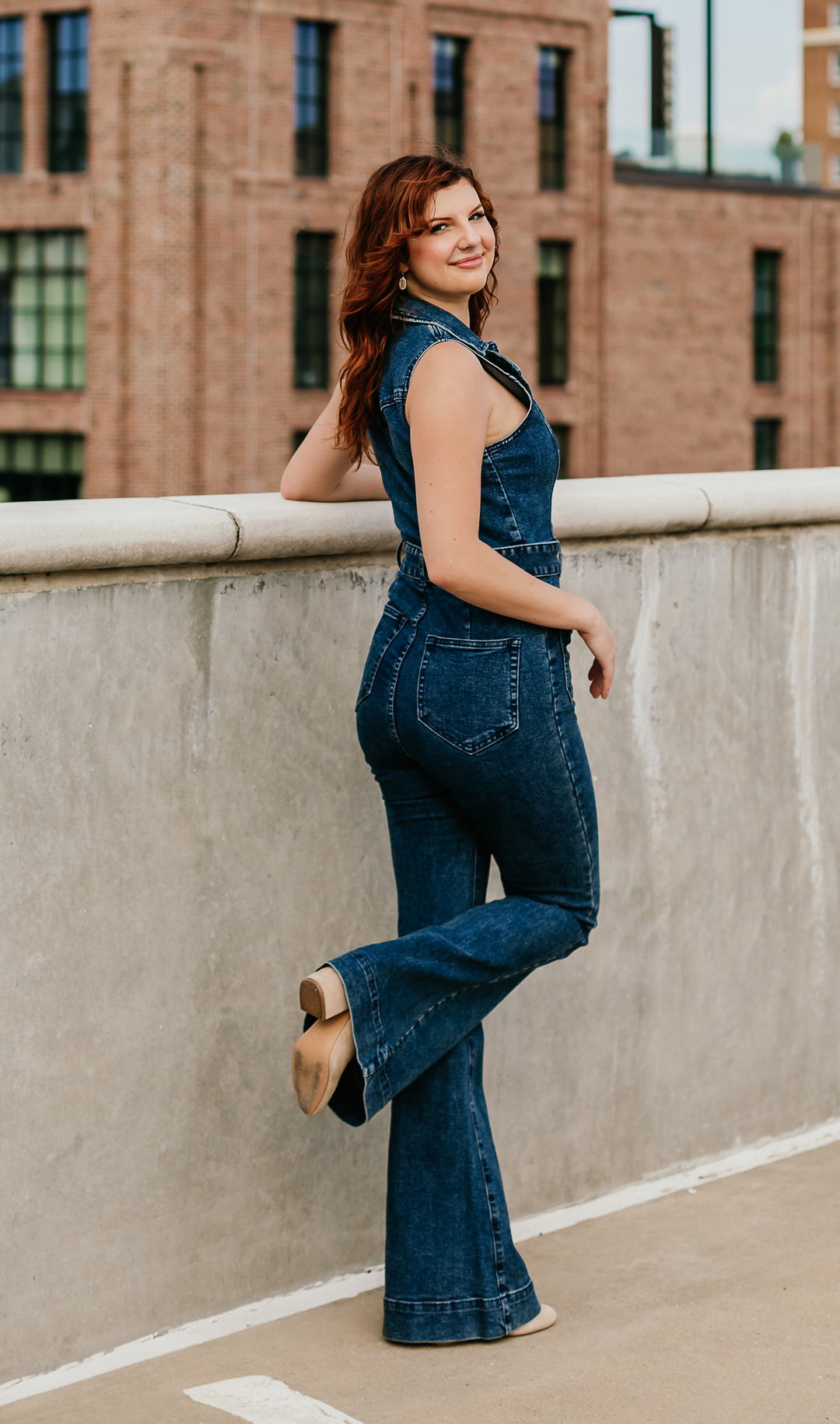 Woman wearing denim flare jumpsuit with Western-inspired styling